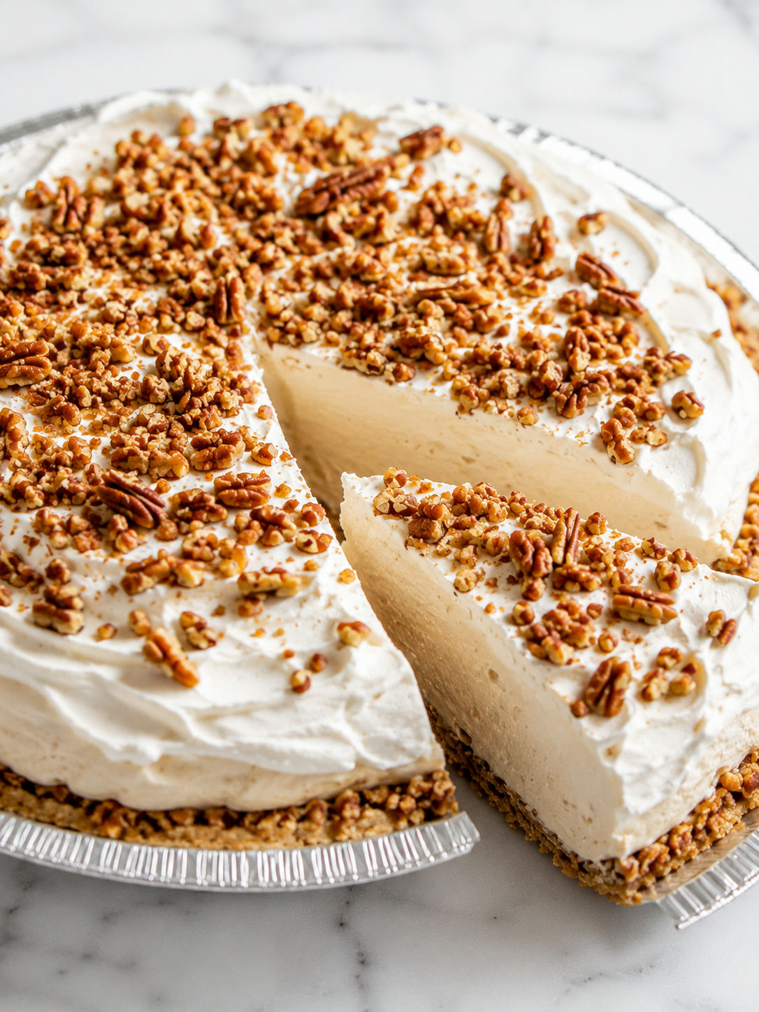 Slice of no-bake maple pecan cream pie with fluffy filling and pecans