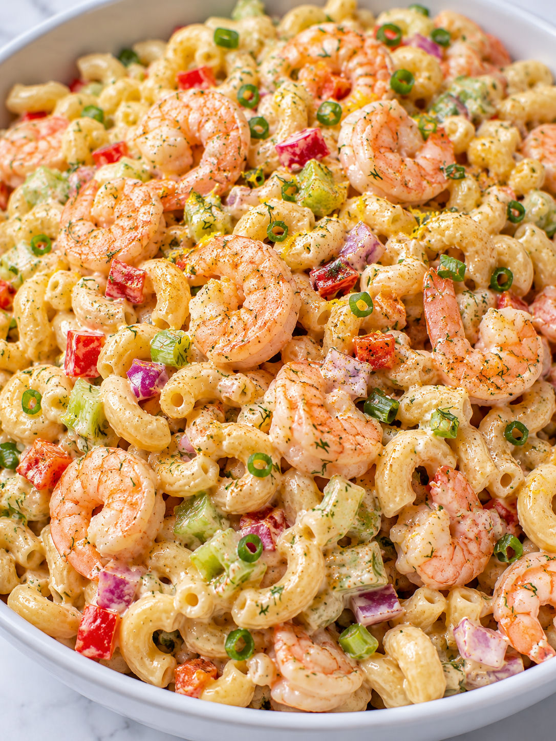 Creamy Old Bay shrimp macaroni salad filling a bowl with dill and lemon