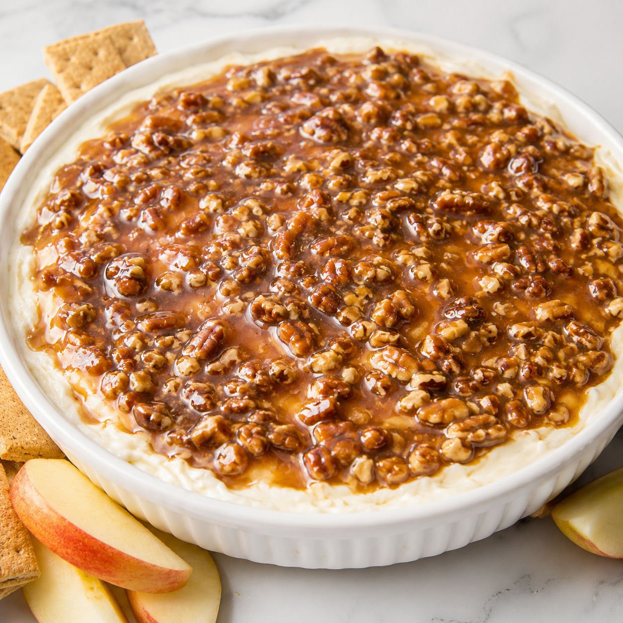 Pecan pie cheesecake dip with glossy pecan topping and graham crackers