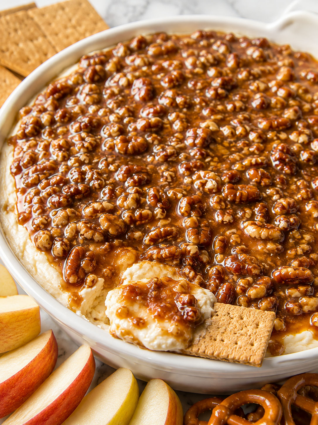 Pecan pie cheesecake dip with a graham cracker scoop and toasted pecans