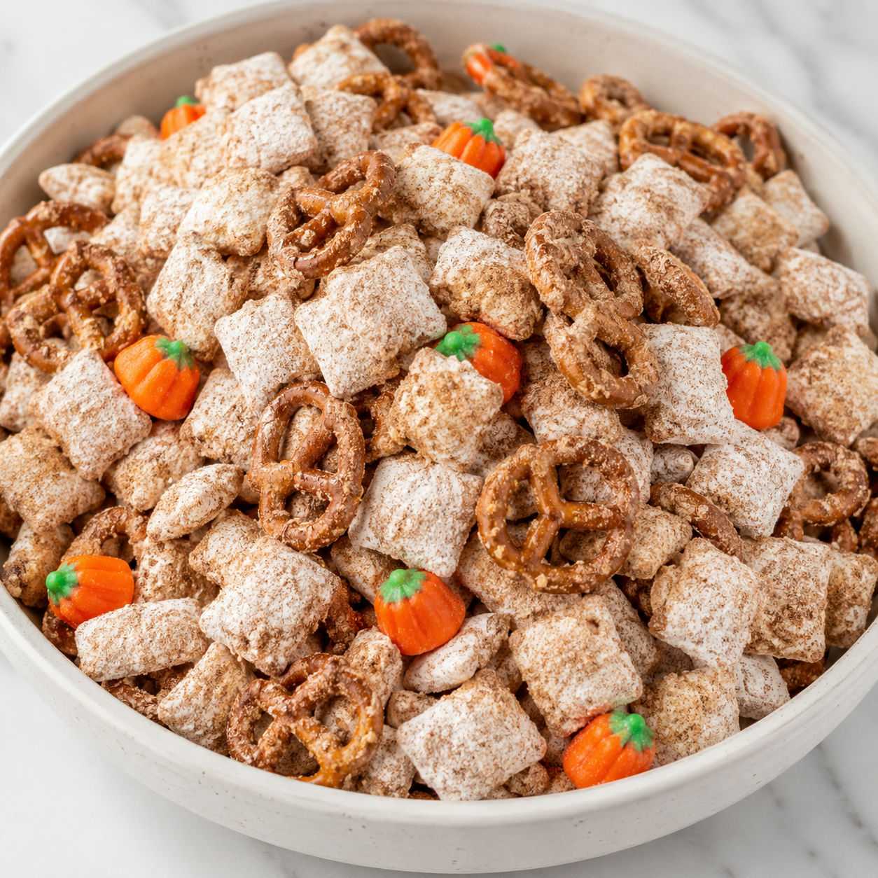 Pumpkin spice puppy chow with pretzels in a cream bowl