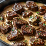 A delicious beef stew with meat and vegetables, served in a black pot.