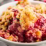 A bowl of fruit with a peach on top.