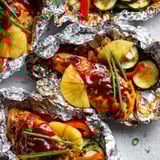 Tender chicken with pineapple chunks, up close on foil.