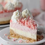 A slice of cake with white frosting and red sprinkles.