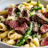 A bowl of pasta with meat and green beans.
