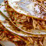 A stack of chicken pita bread with sauce.