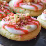 A cookie with white frosting and red strawberry topping.