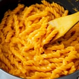 A spoon is in a pot of macaroni and cheese.