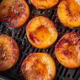 Sliced peaches on a grill.