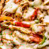 A close up of a pizza with peppers and cheese.