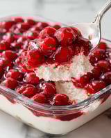 A spoon is in a bowl of red berries.